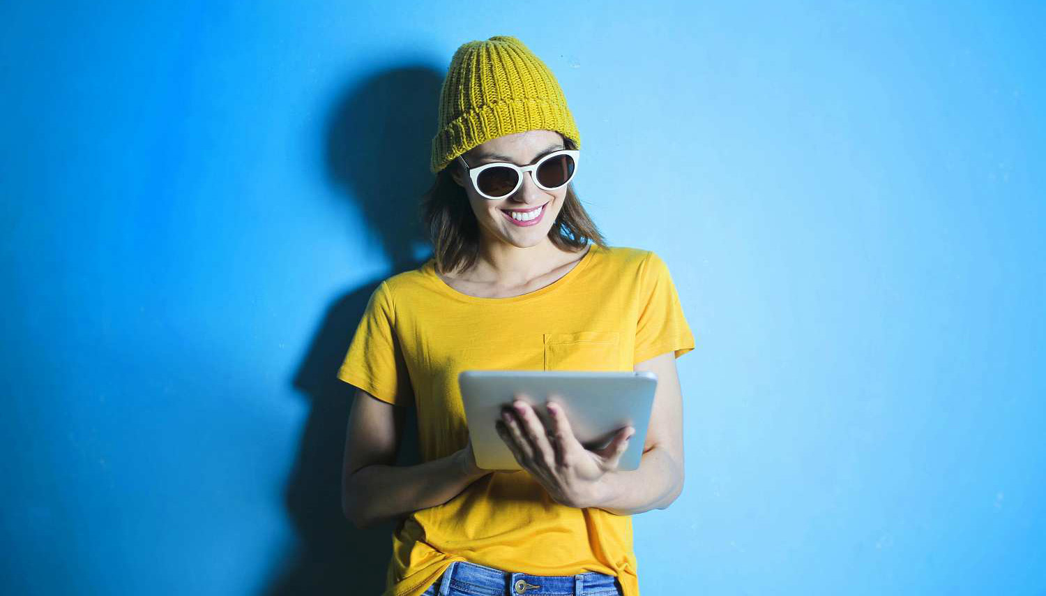 Mädchen mit gelber Kleidung, Brille und E-Book in der Hand